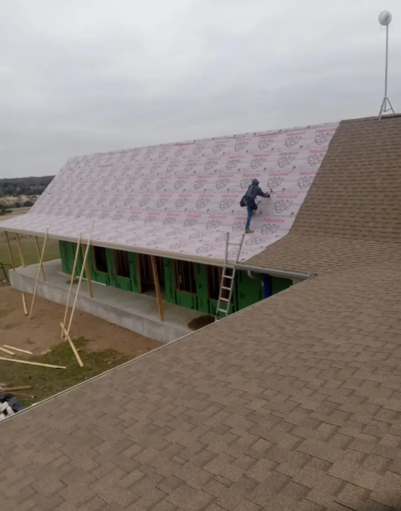 Worker preparing underlayment for a metal roof installation in Galax